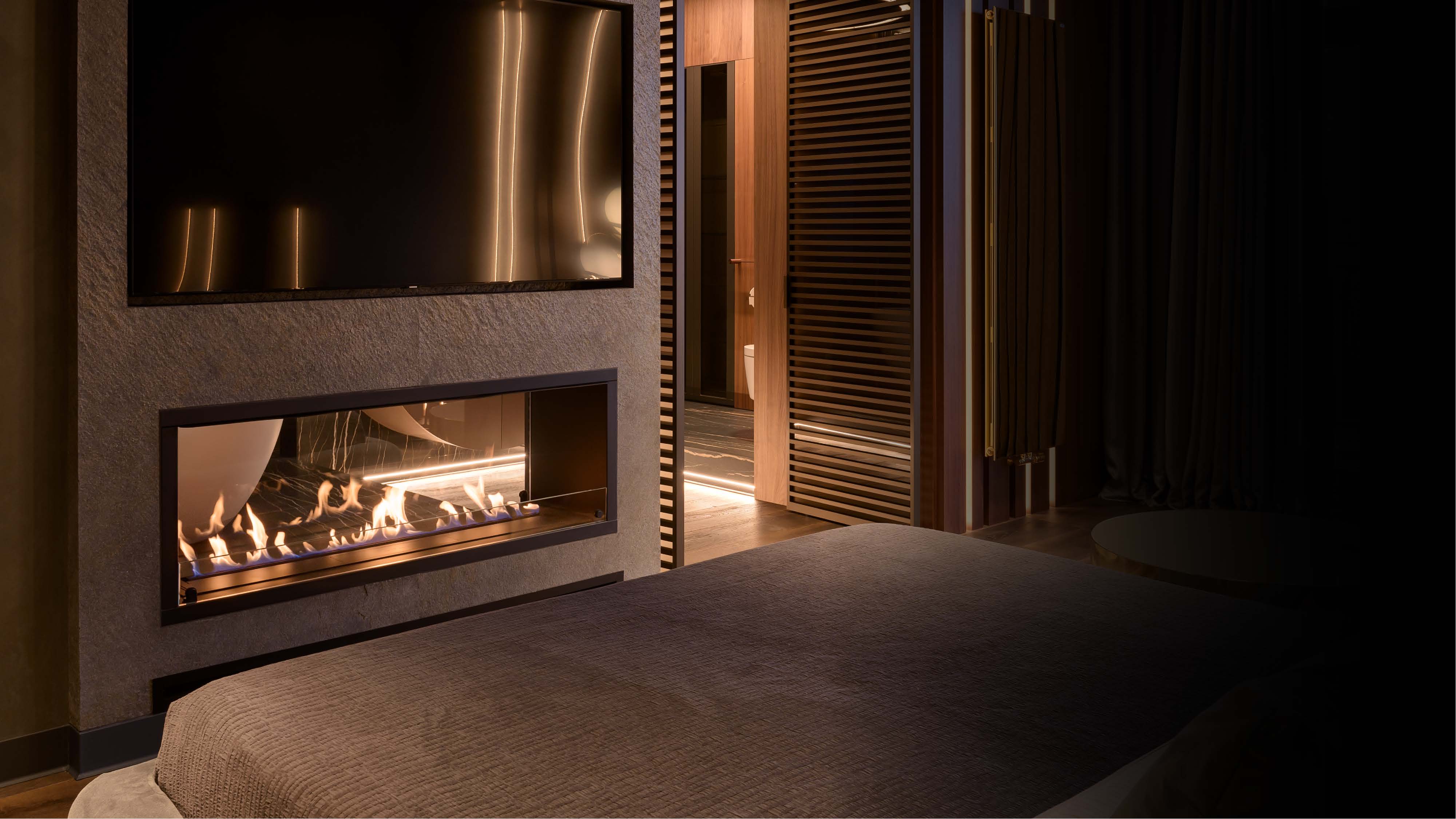 A see-through bioethanol fireplace separating two softly lit interior spaces.