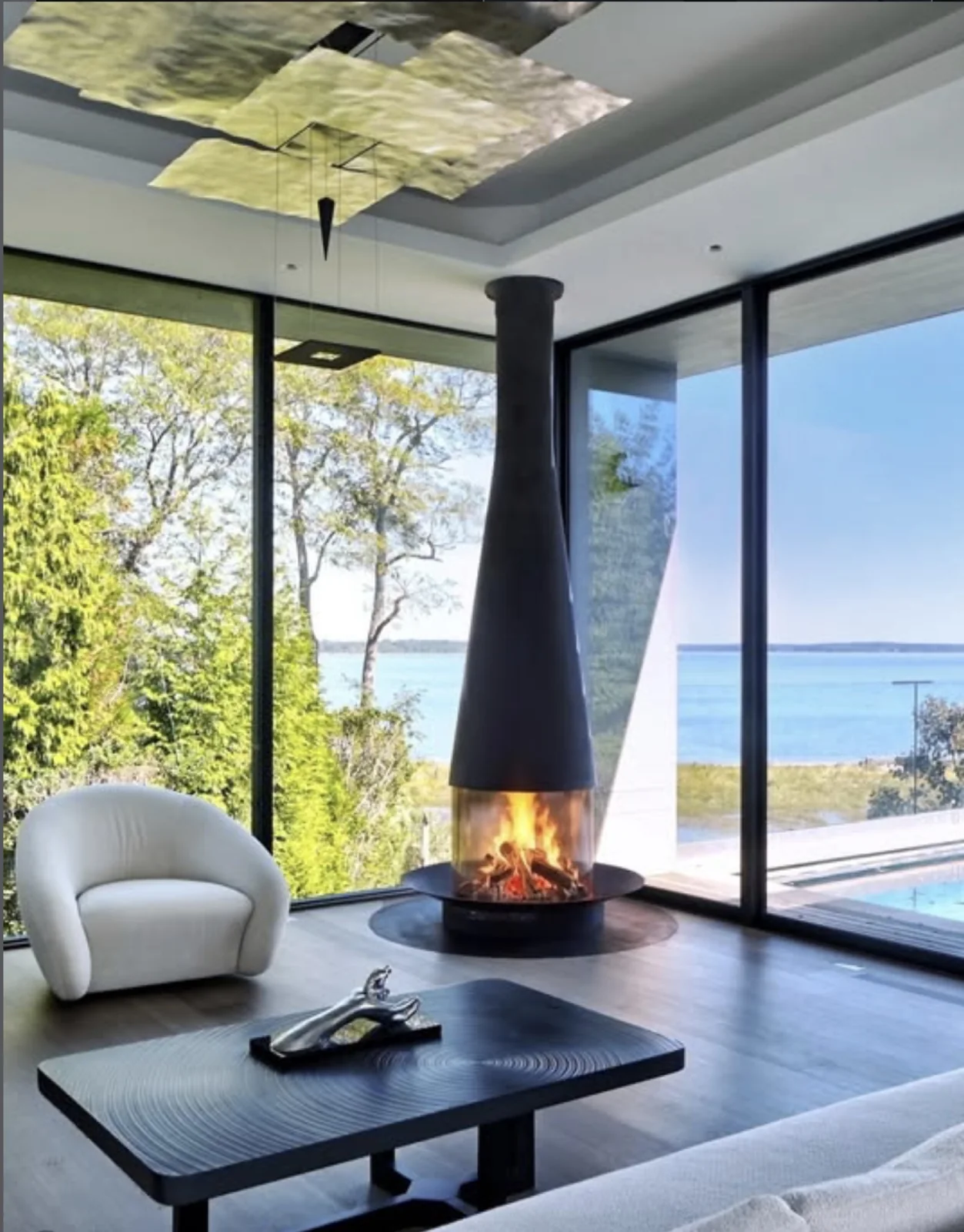 A fireplace in a calm living room with a view out to the sea.